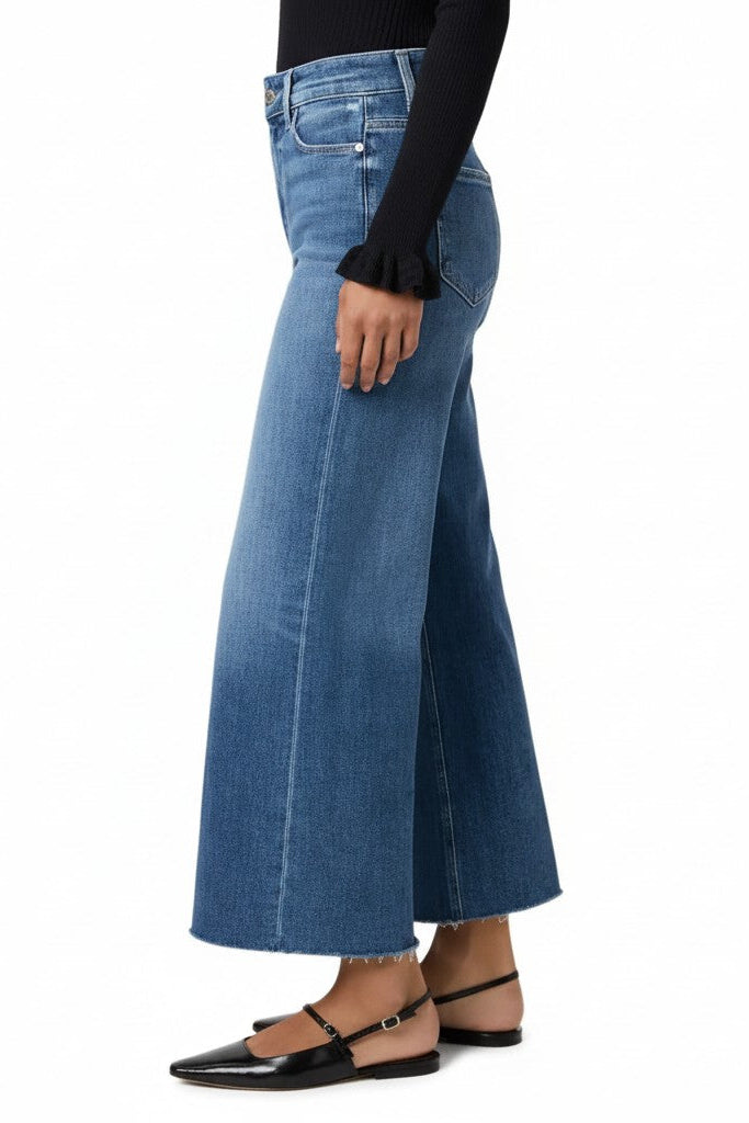 Woman wearing blue wide-leg jeans on a white background.