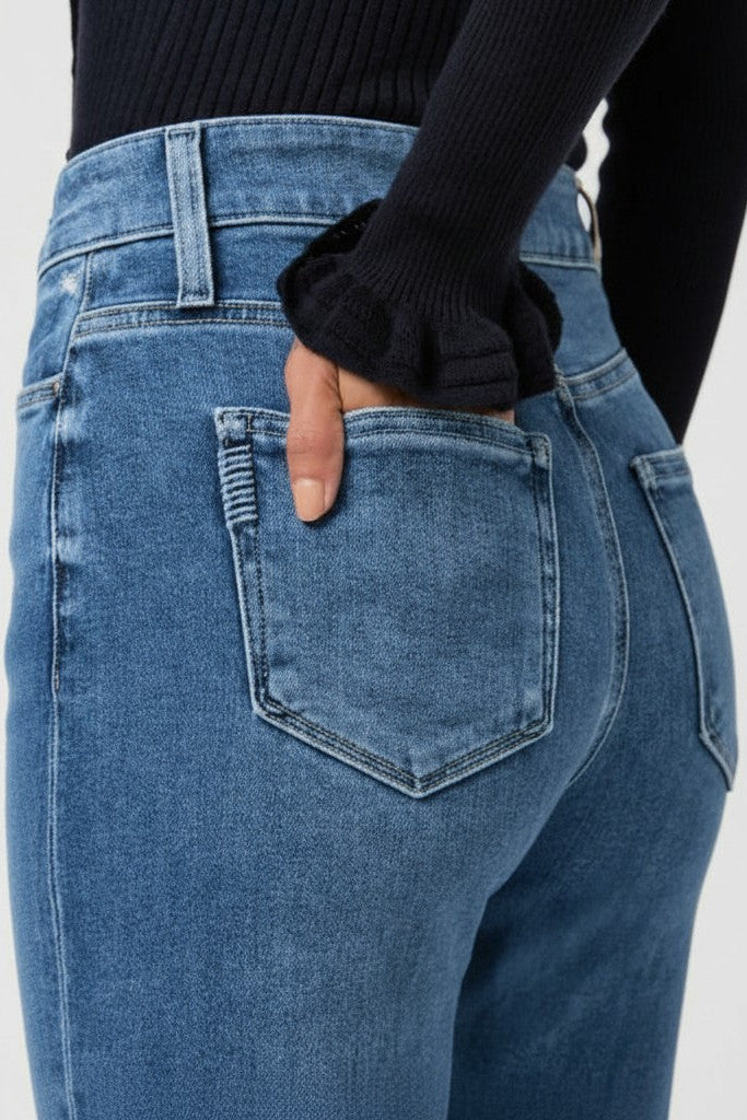Close-up woman wearing blue jeans with a plain background