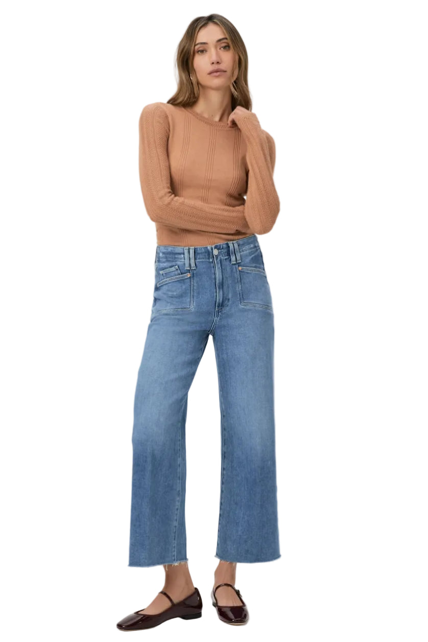 Woman wearing a brown sweater and blue jeans on a white background.
