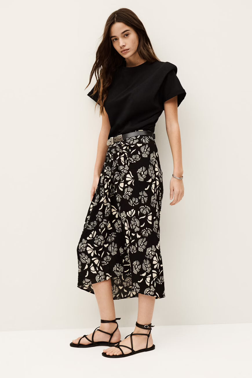 Woman wearing a black top and floral skirt on a white background