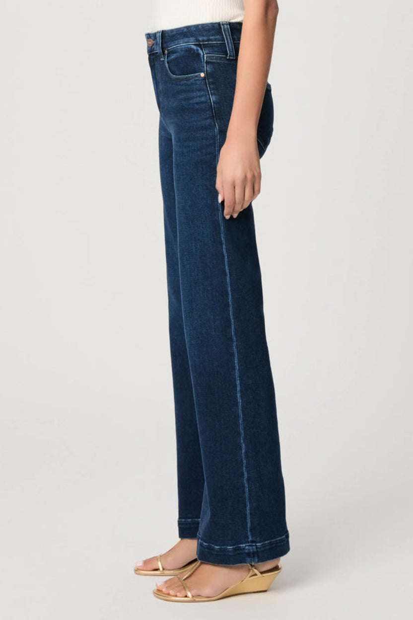 Person wearing dark blue jeans on a light gray background.