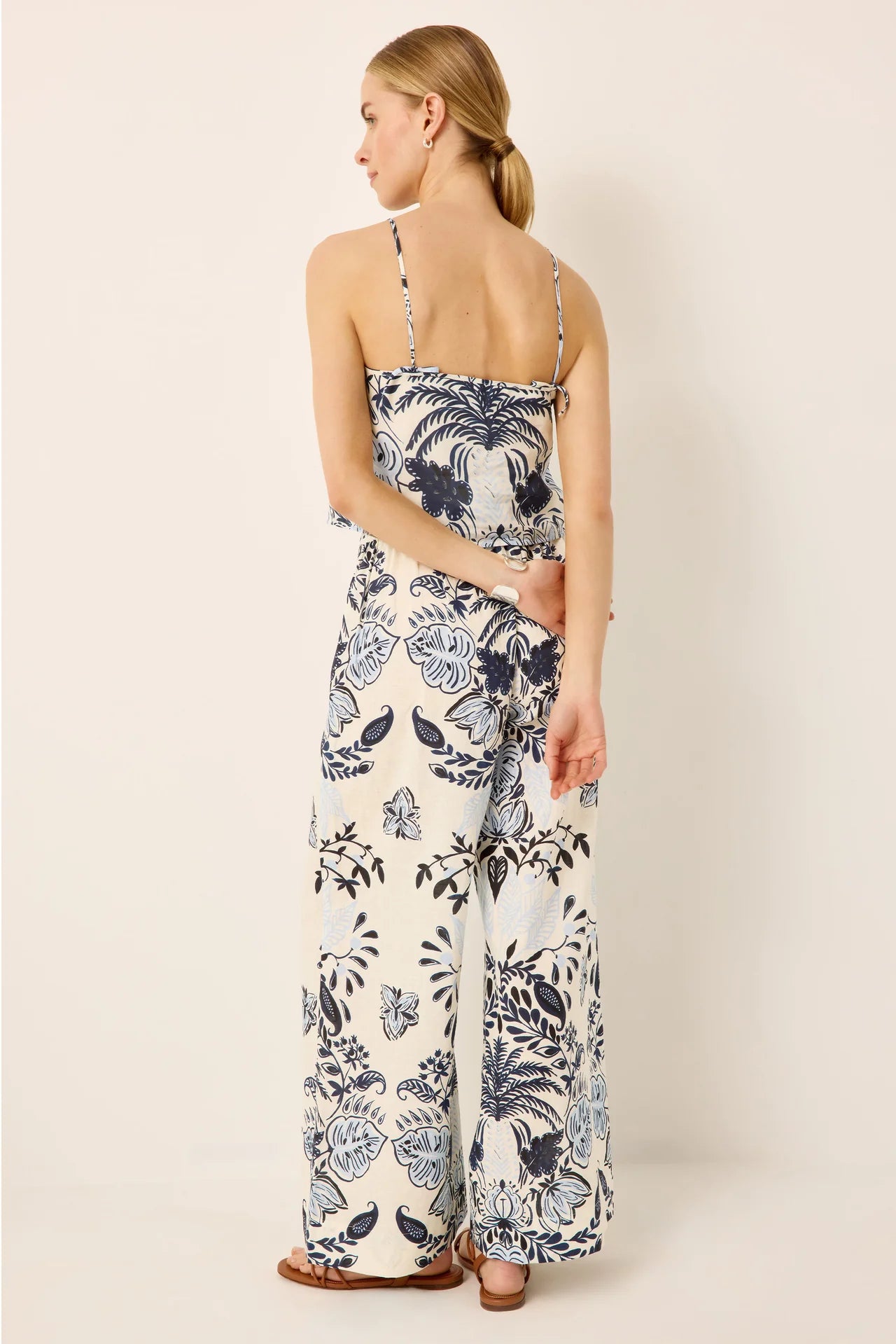 The back of a woman wearing a matching floral top and pants on a plain background.