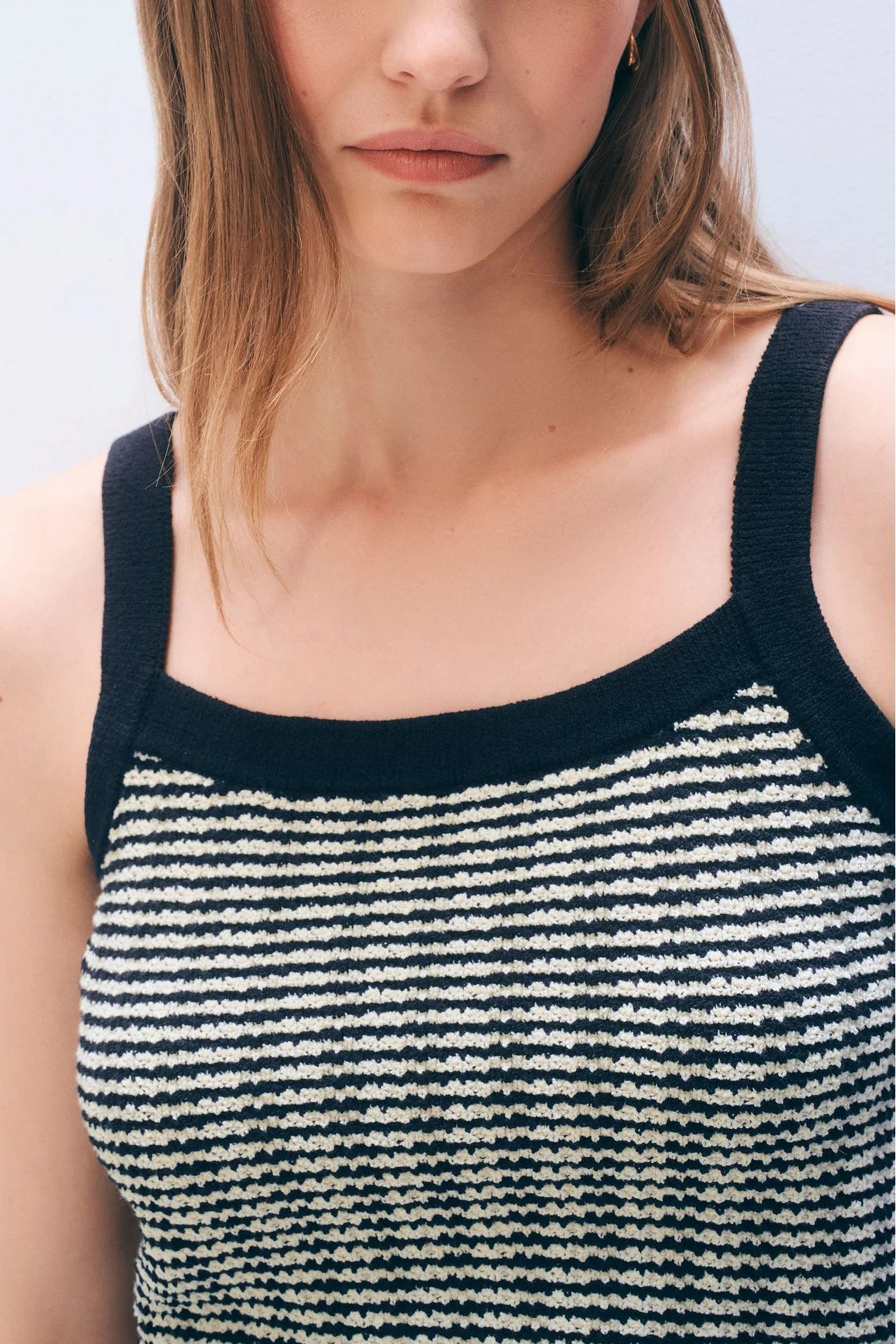 Woman wearing a midnight blue and ivory striped sleeveless top against a light background.
