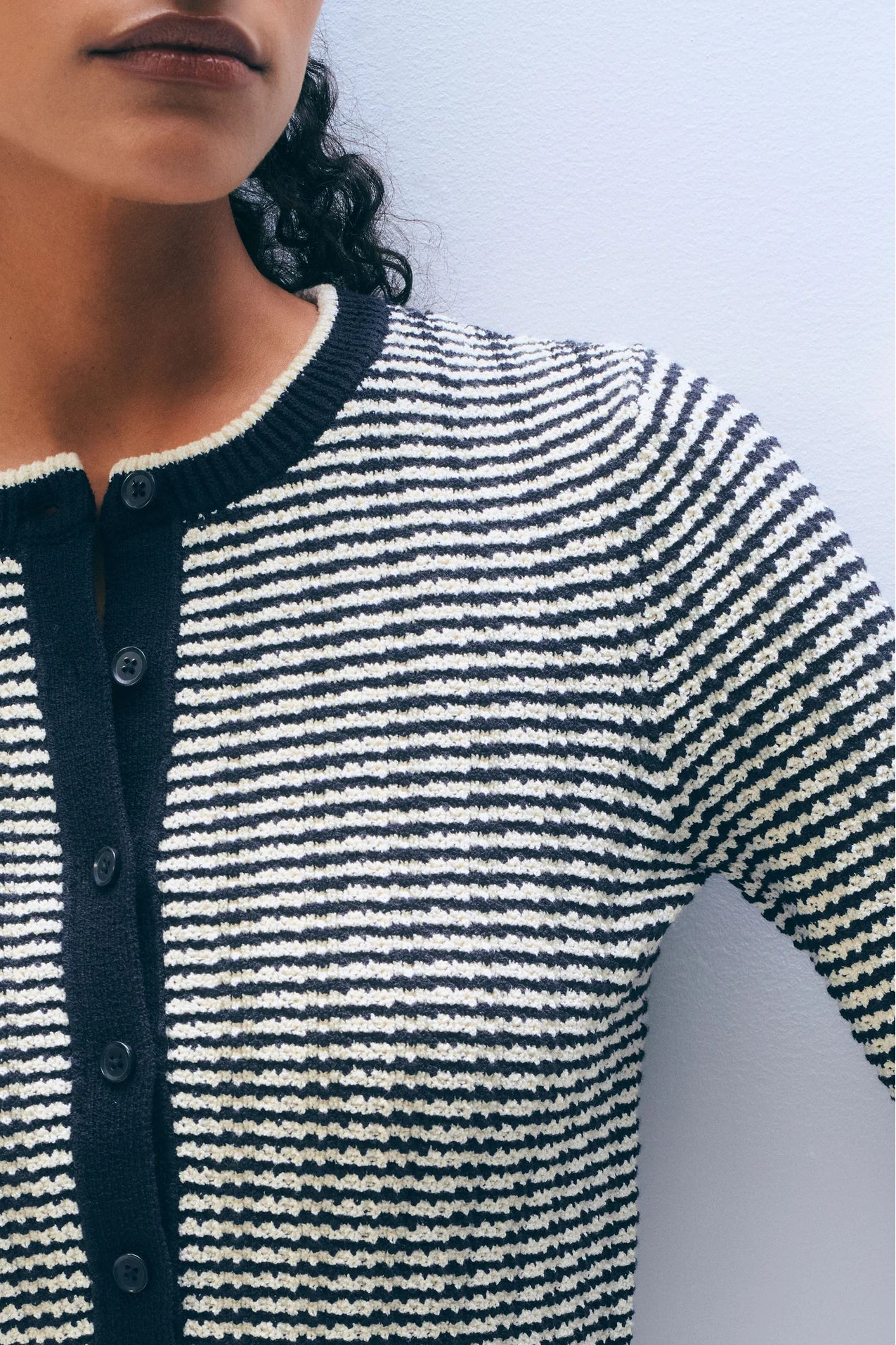 Close-up of a woman wearing a midnight blue and ivory patterned cardigan on a plain background.