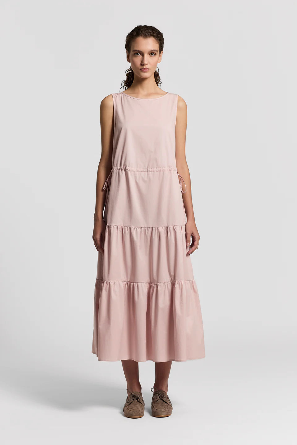 Woman wearing a pink sleeveless dress on a white background.