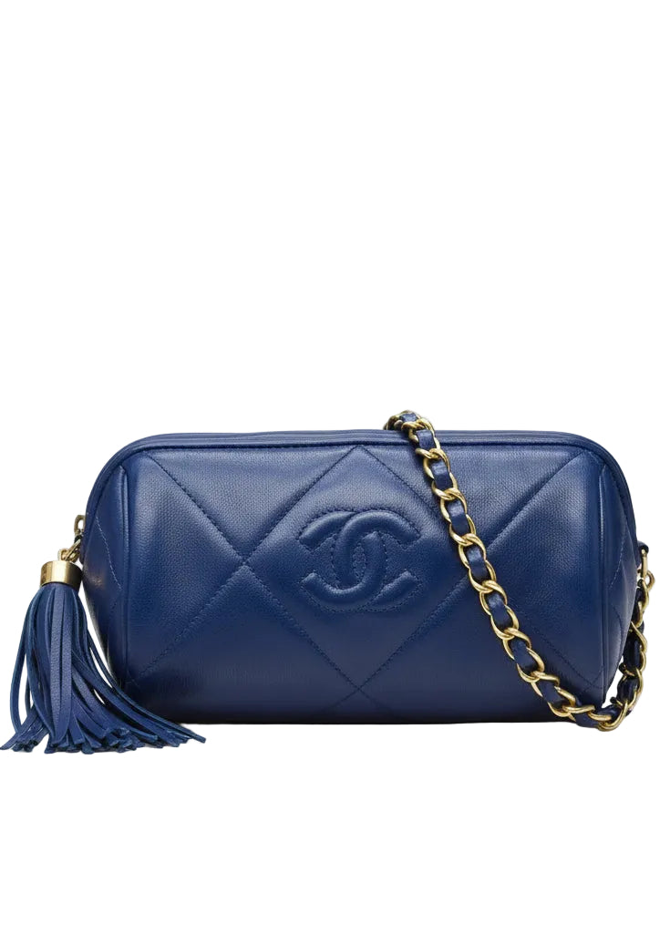 Blue quilted handbag with gold chain and tassel on a white background.