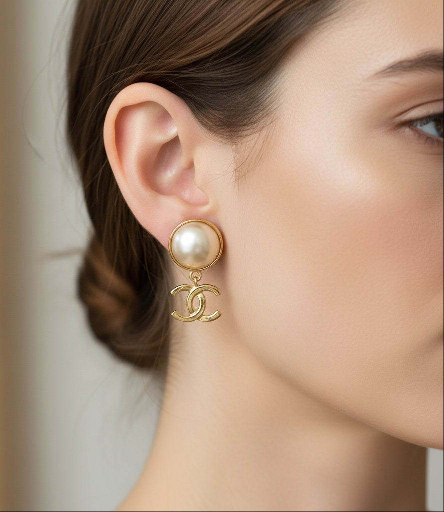 Close-up of a woman wearing a Chanel earring with a pearl-like charm.