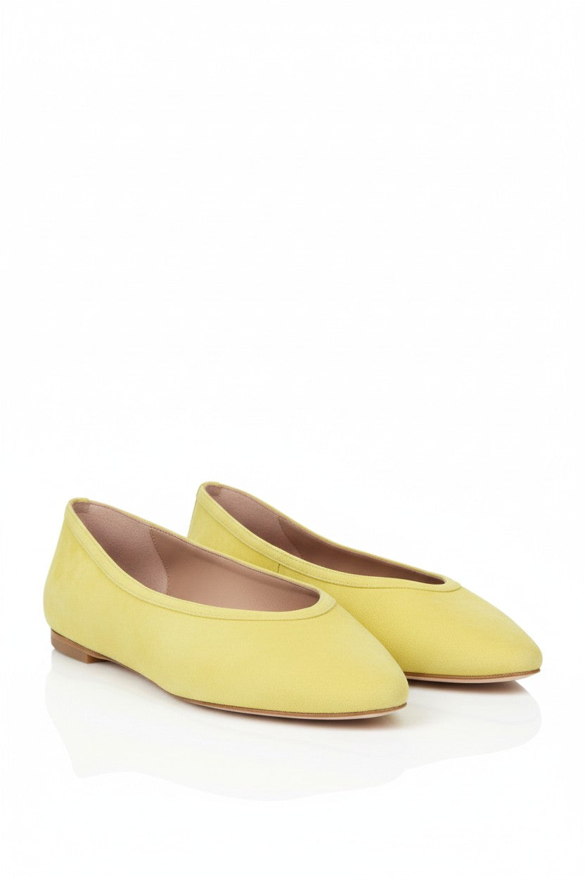 Pair of yellow suede flats on a white background.