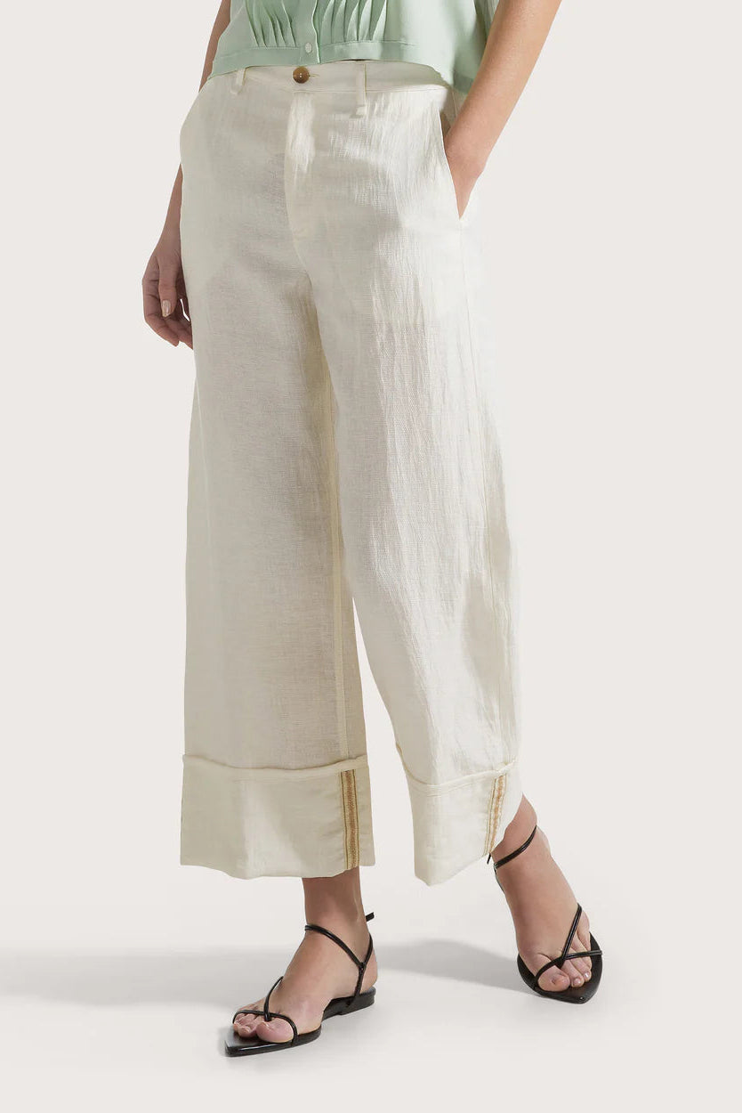 Woman wearing light-colored wide-leg pants on a white background.