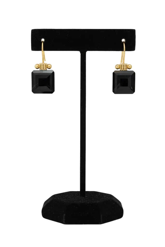 Black square earrings with gold detail on a black stand against a white background.