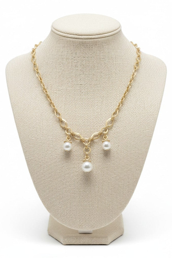 Gold necklace with pearls on a beige mannequin bust against a white background.
