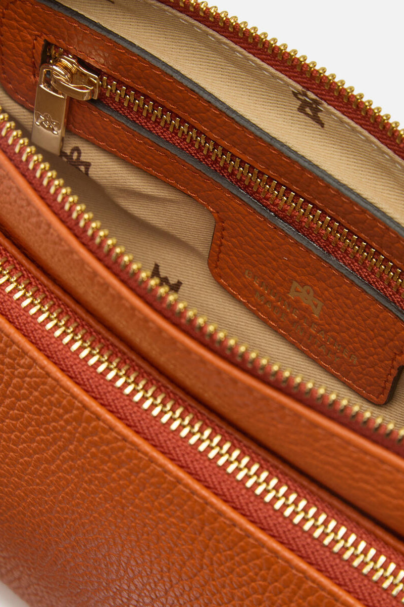 Close-up of a orange leather bag with gold zipper and visible brand logo.