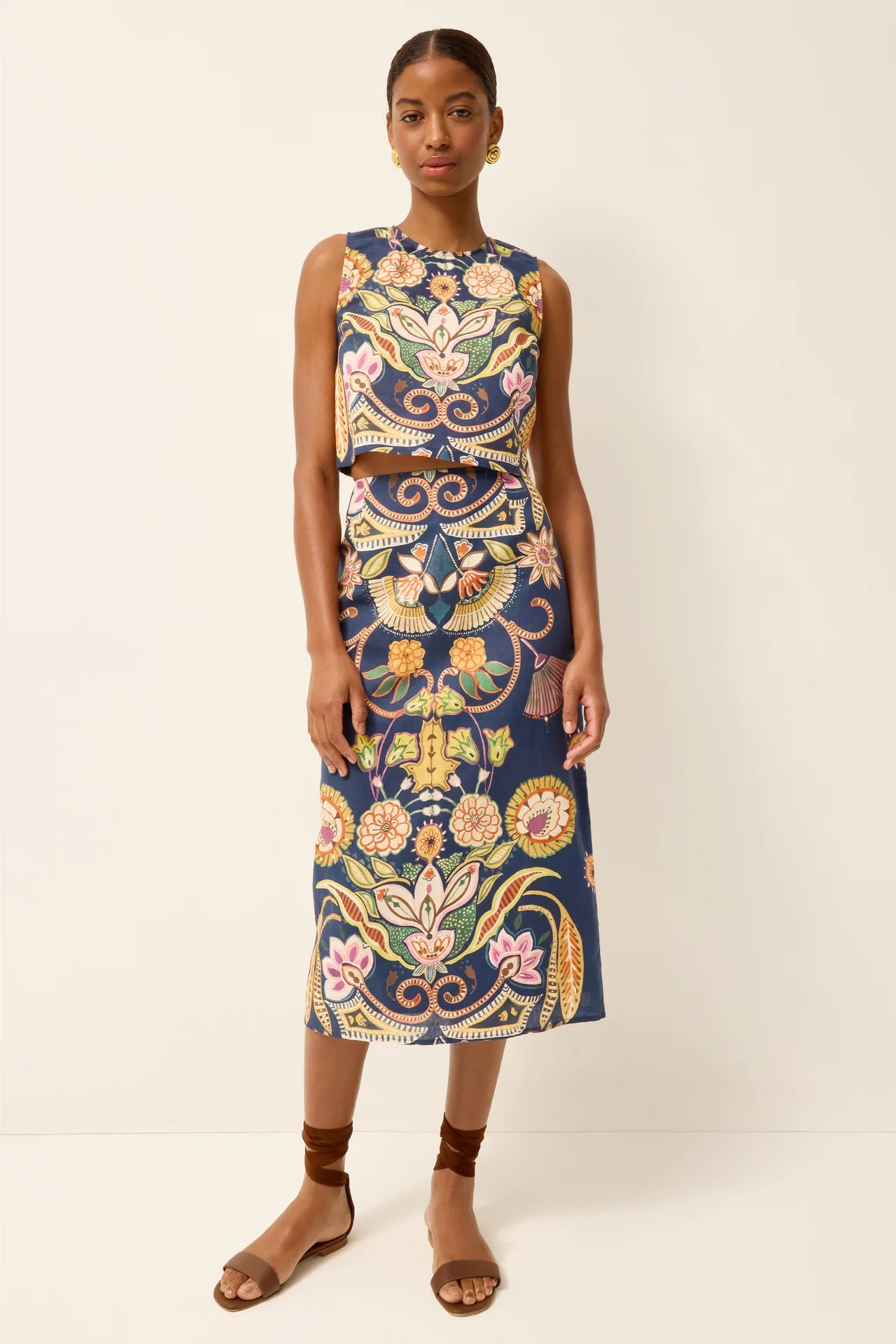 Woman wearing a sleeveless floral dress on a white background.