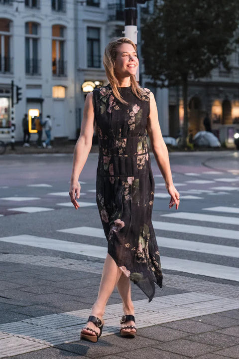 Woman wearing a floral dress with black platform sandals crossing a street in an urban setting.