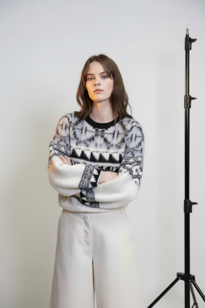 Model wearing a patterned sweater with a white background and photography equipment.