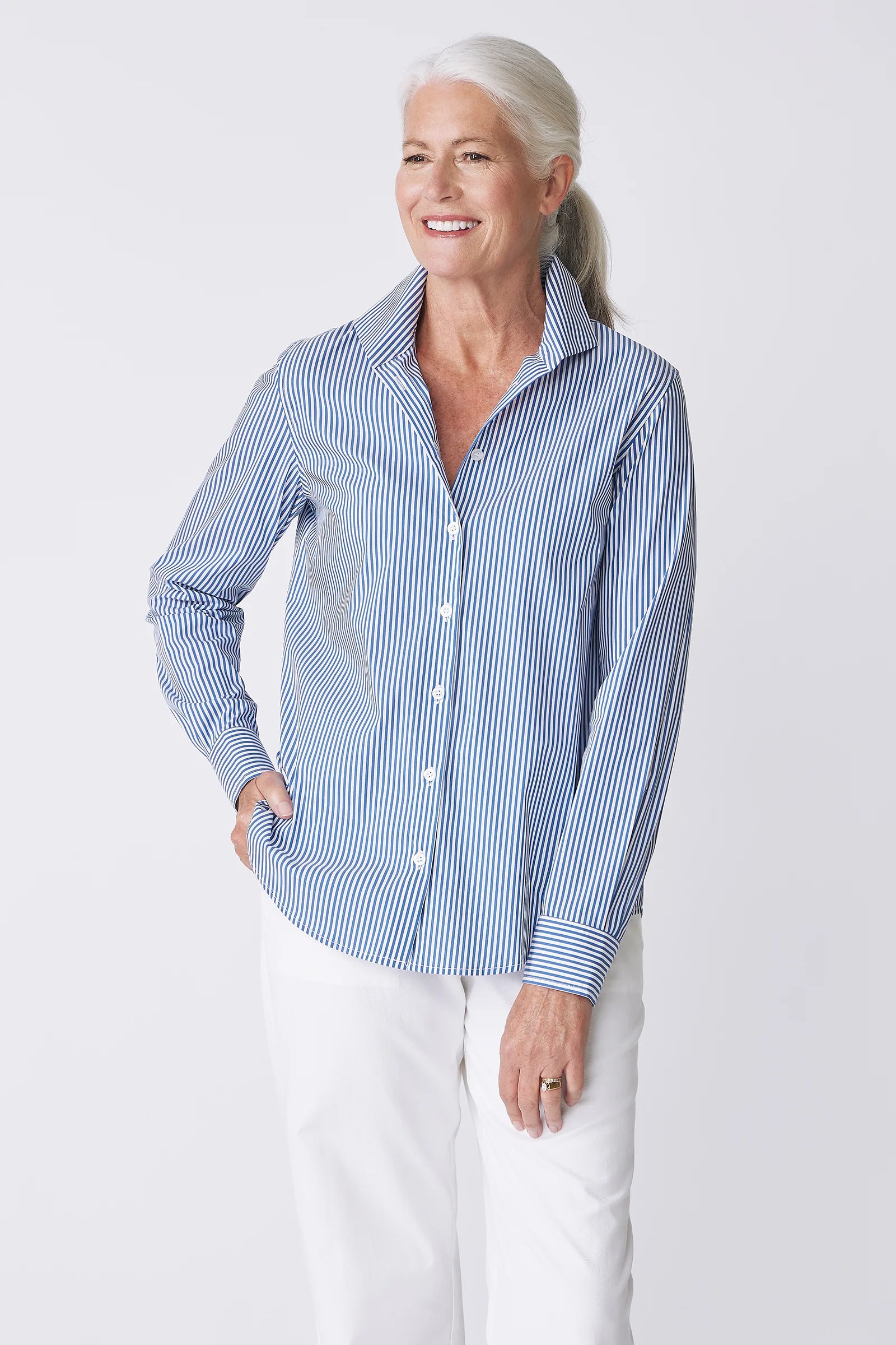 Woman wearing a blue and white striped shirt with a gray pocket on a light gray background.