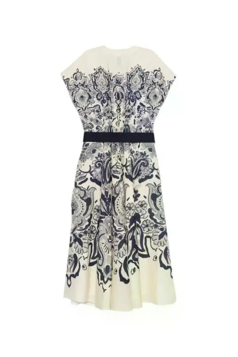 The back of an off white dress with a navy floral pattern and a navy belt.