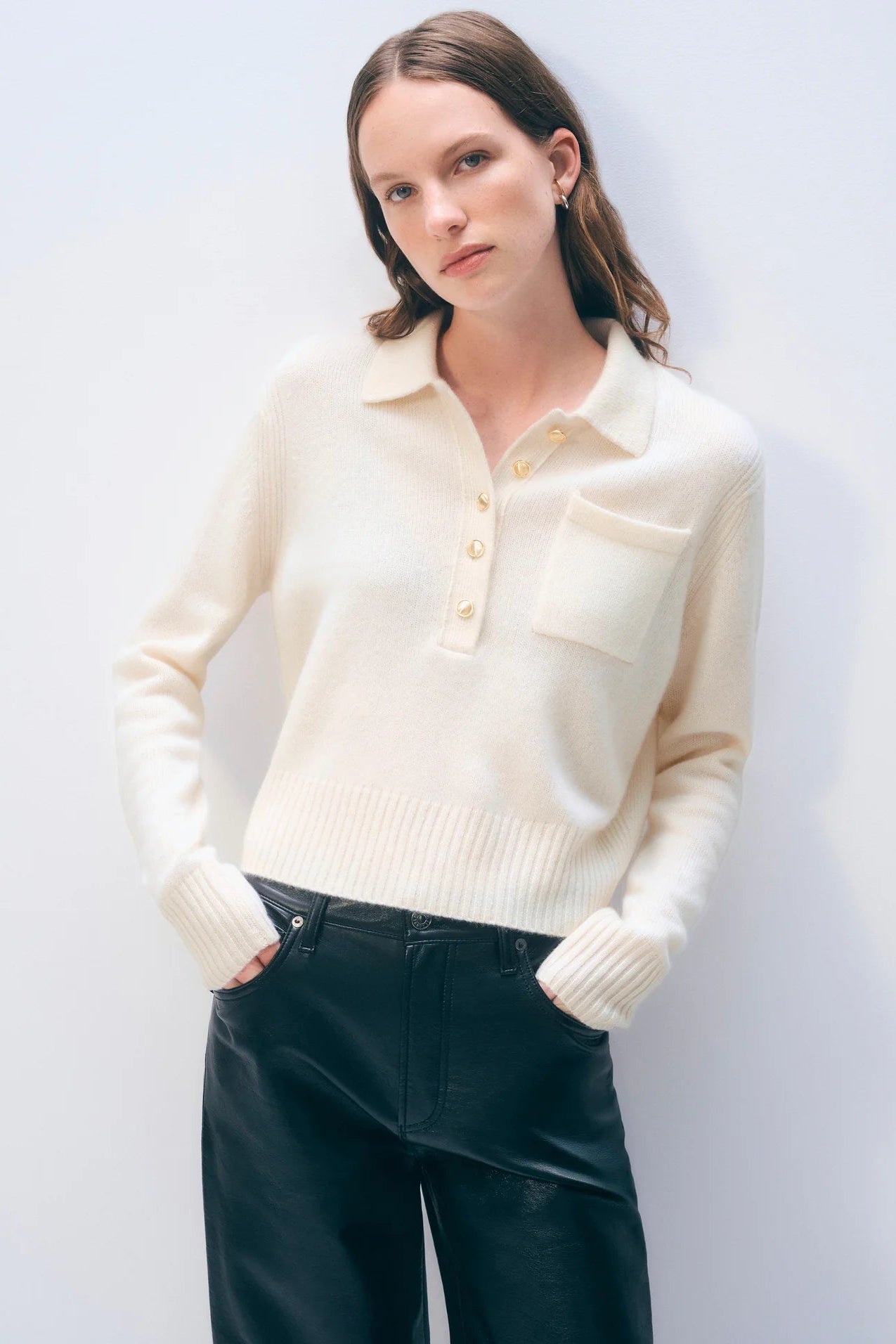 Woman wearing a cream-colored sweater with a collar against a white background.