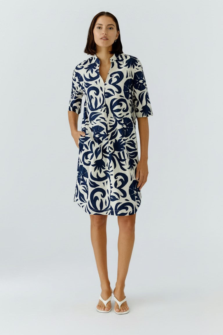 Woman wearing a blue and white patterned dress on a white background.