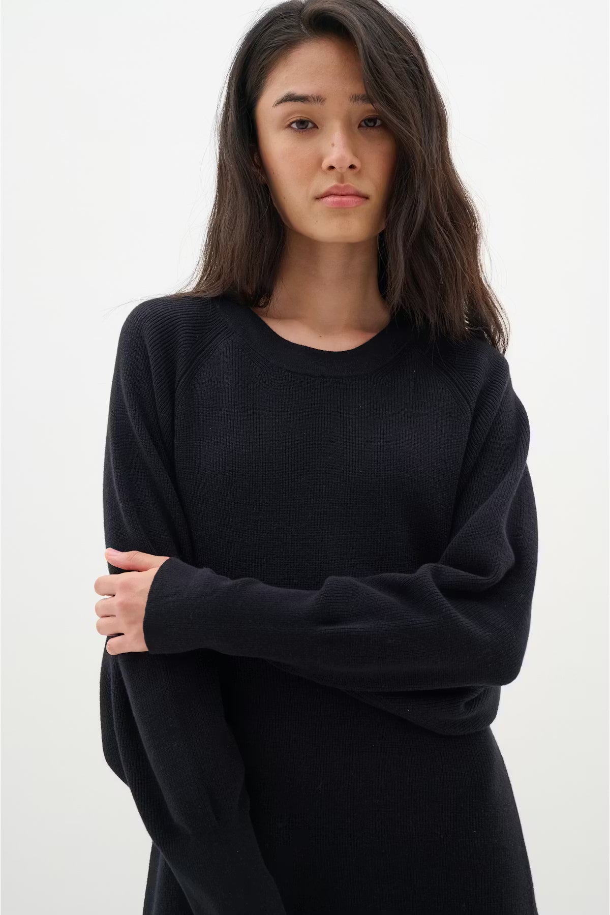 Woman wearing a black sweater against a white background.