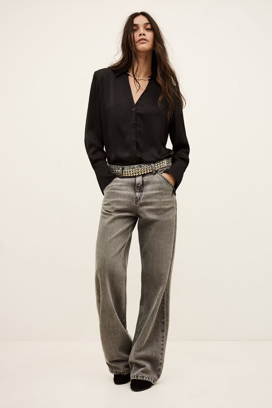 Woman wearing a black blouse and gray flared jeans on a white background