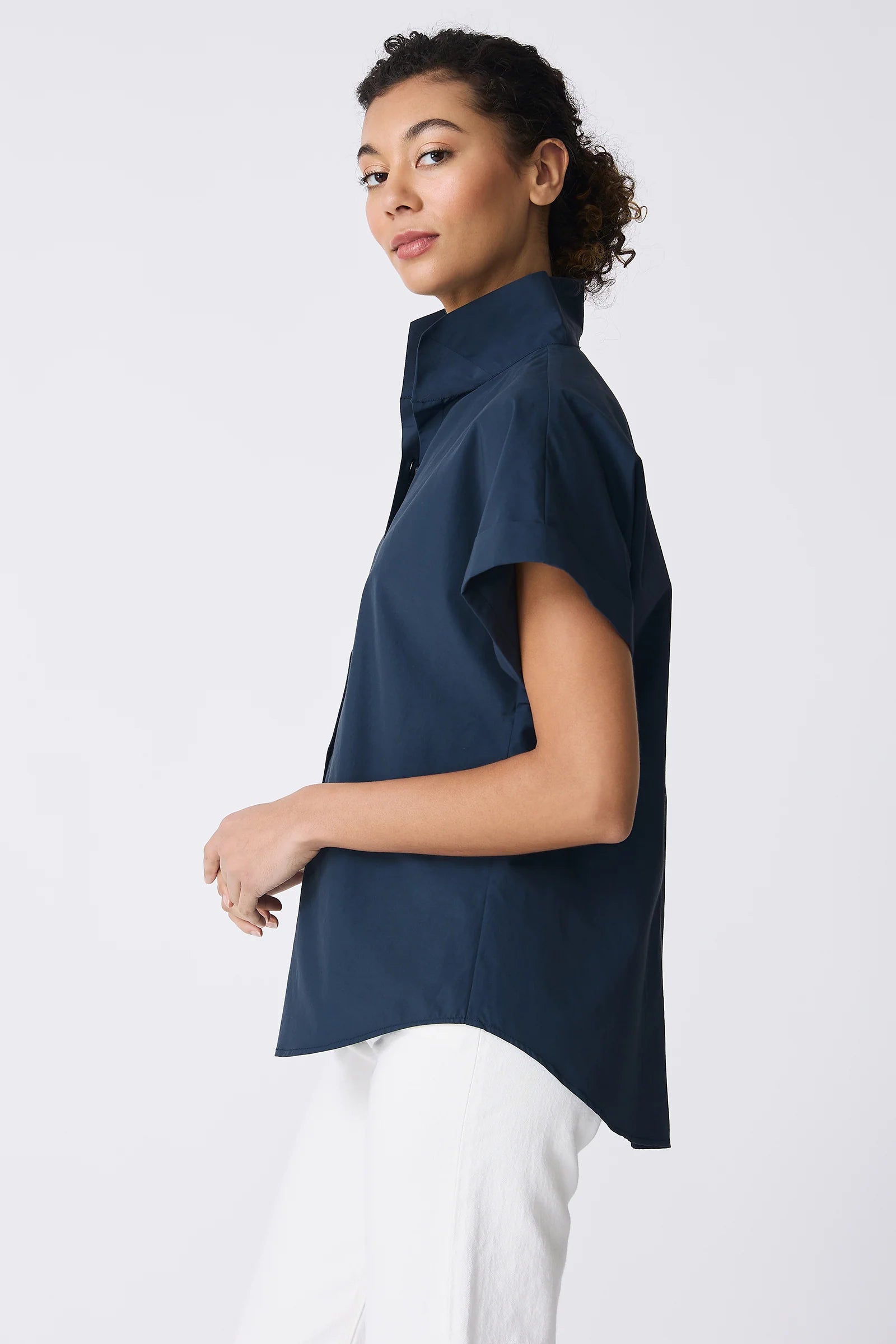 Woman wearing a navy blue short sleeve top against a white background.