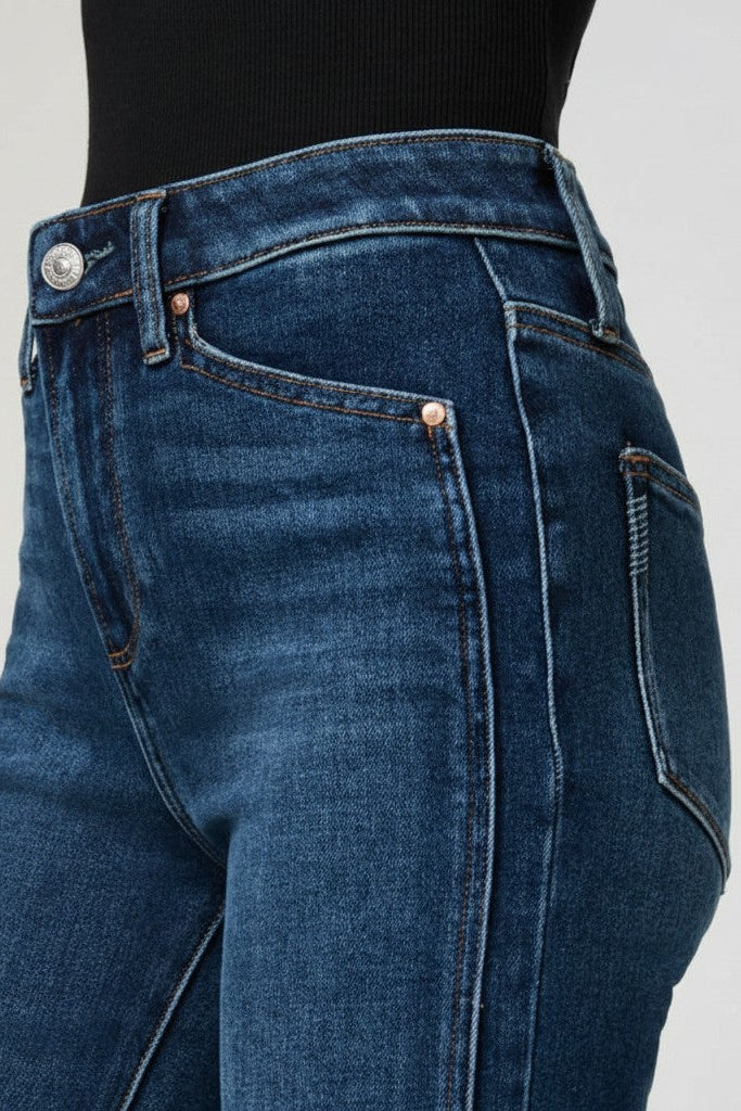 Close-up of a woman wearing blue jeans on a plain background.