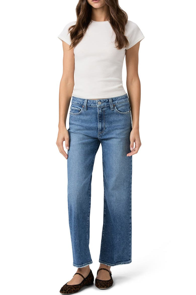 Woman wearing a white t-shirt and blue jeans on a white background.
