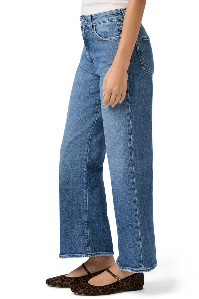 Side view of a woman wearing blue jeans on a white background.