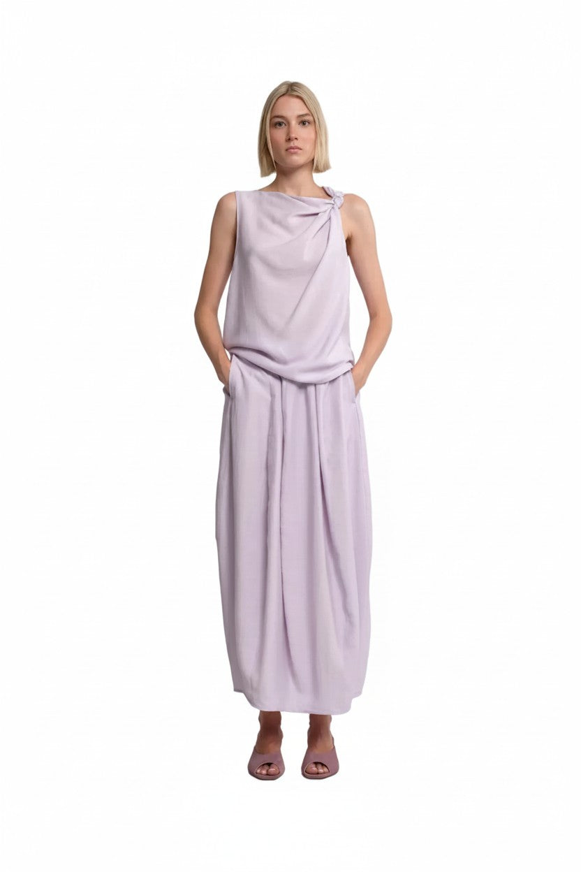 Woman wearing a lilac colored top and skirt on a white background.