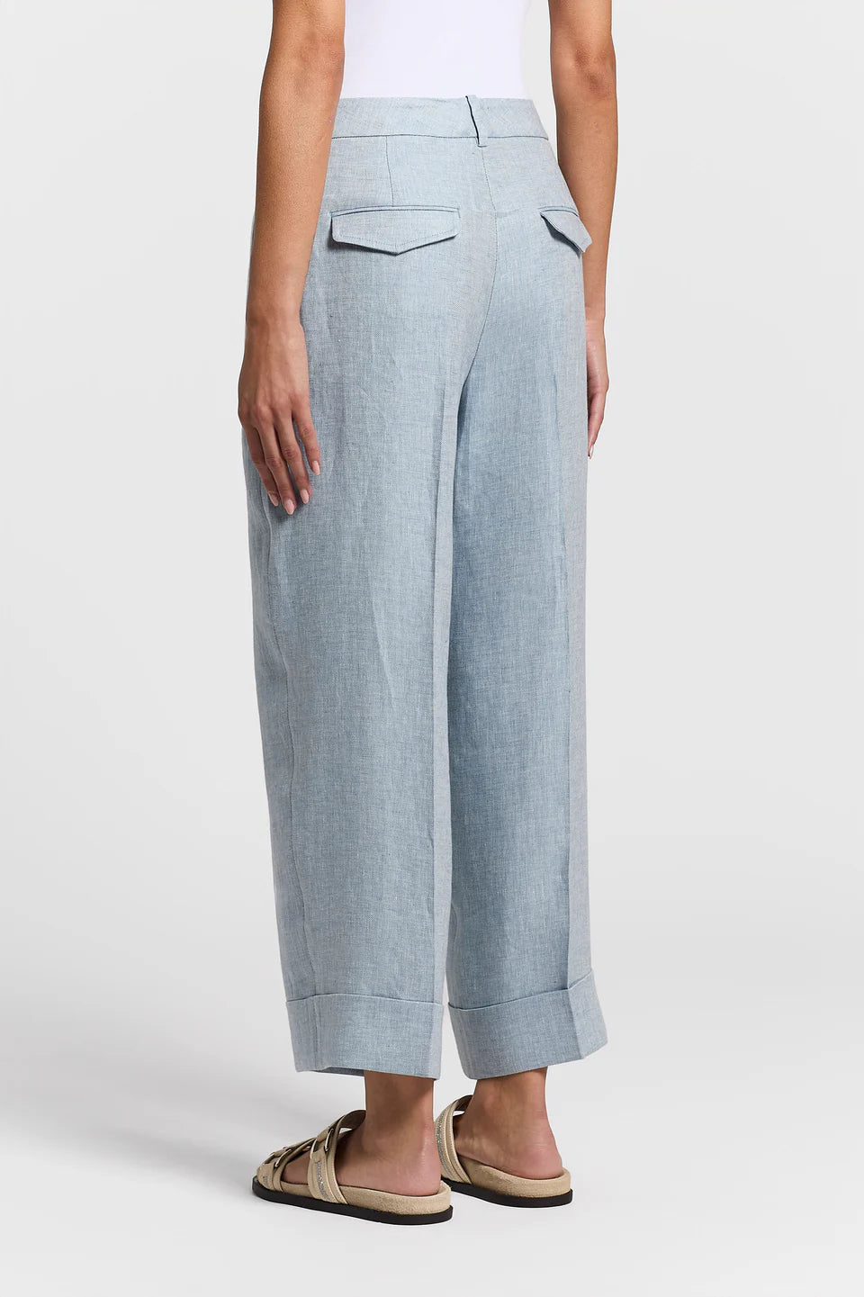 The back of a woman wearing blue pants on a white background.