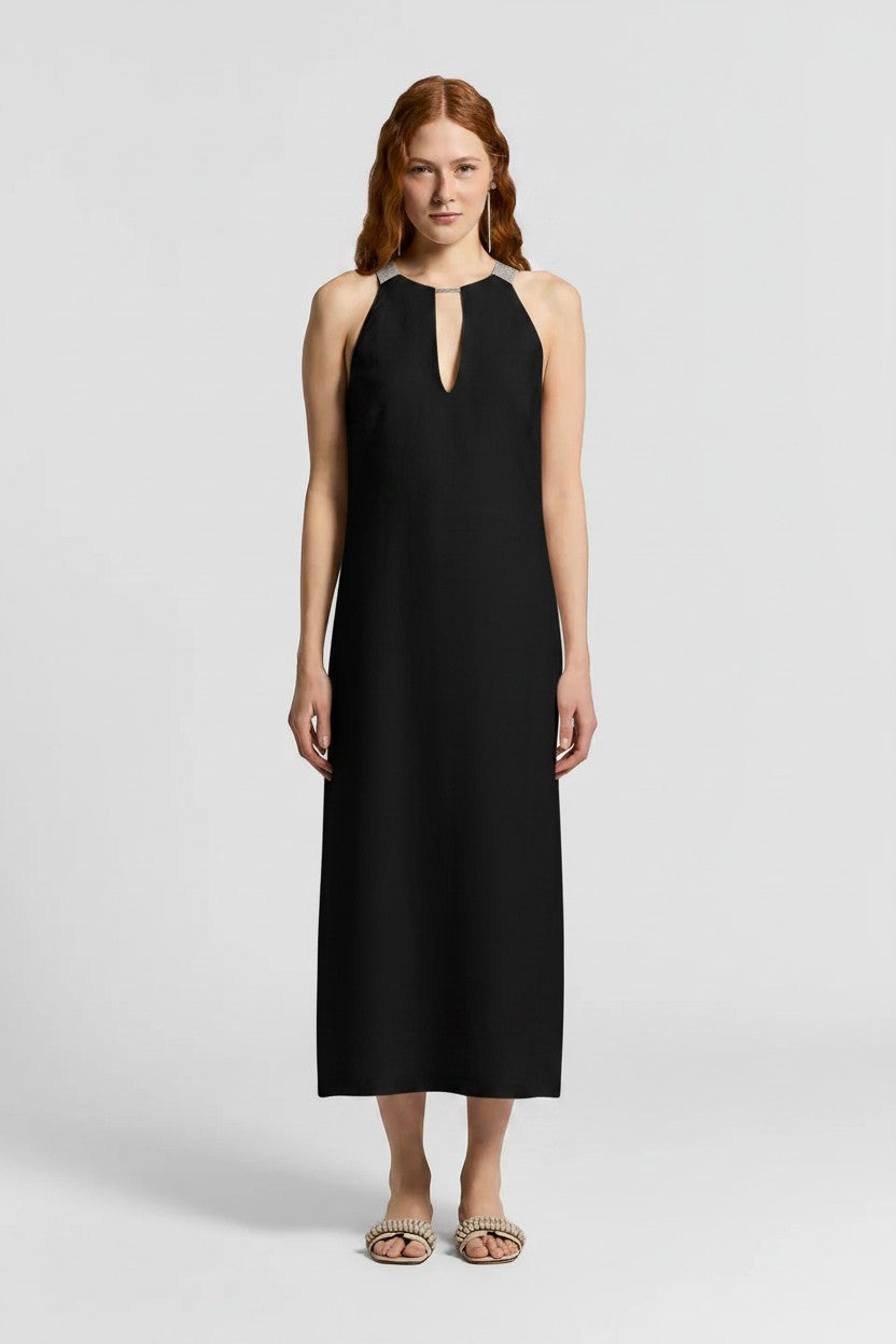 Woman wearing a black dress with sparkle detailing along the neckline on a plain background.