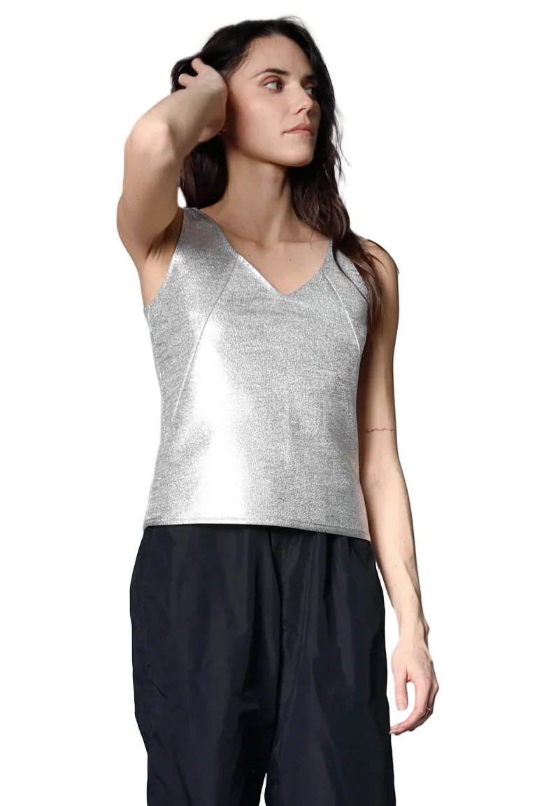 Woman wearing a silver sleeveless top and black pants on a white background.