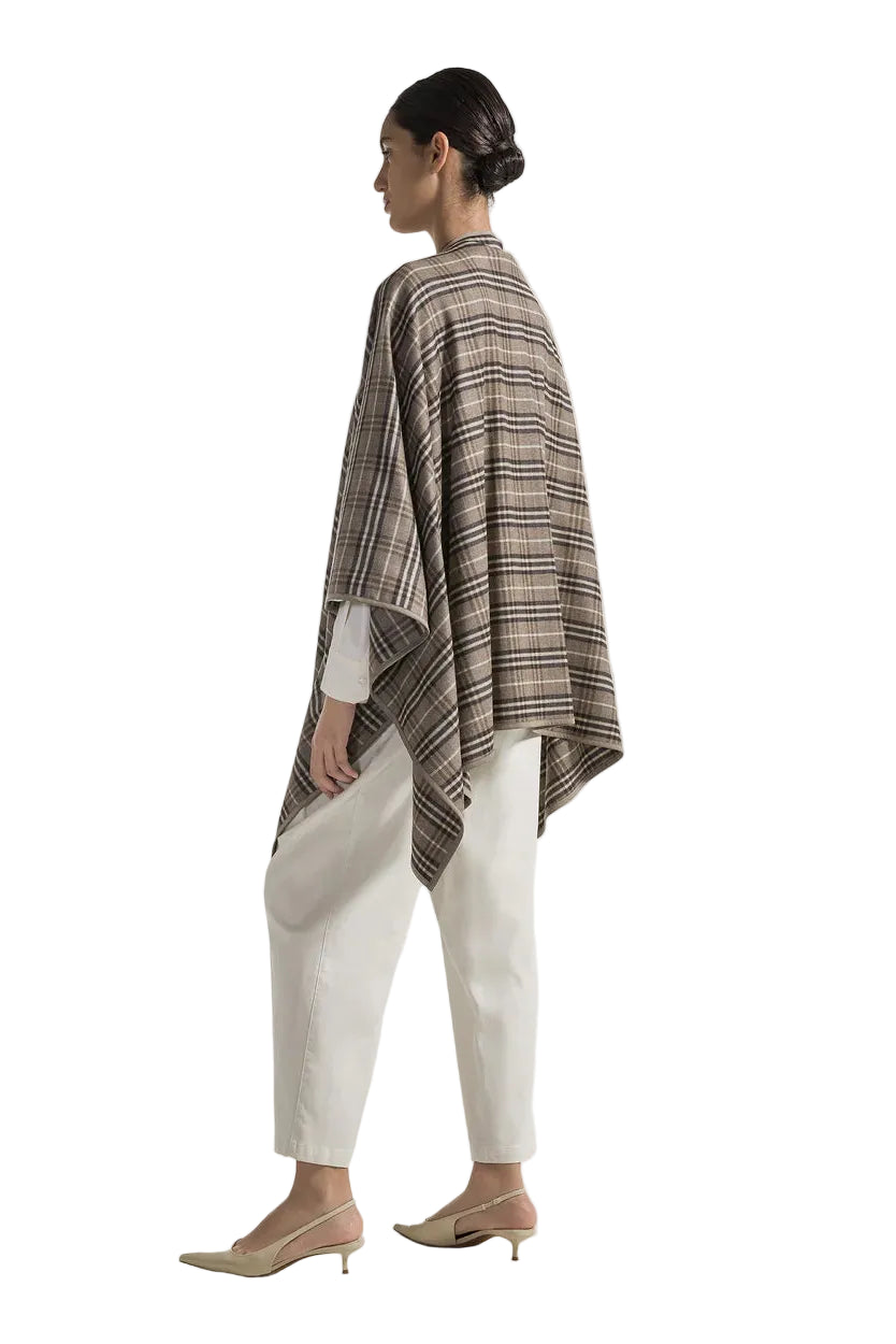 Woman wearing a multicolored plaid poncho over a white outfit on a white background.