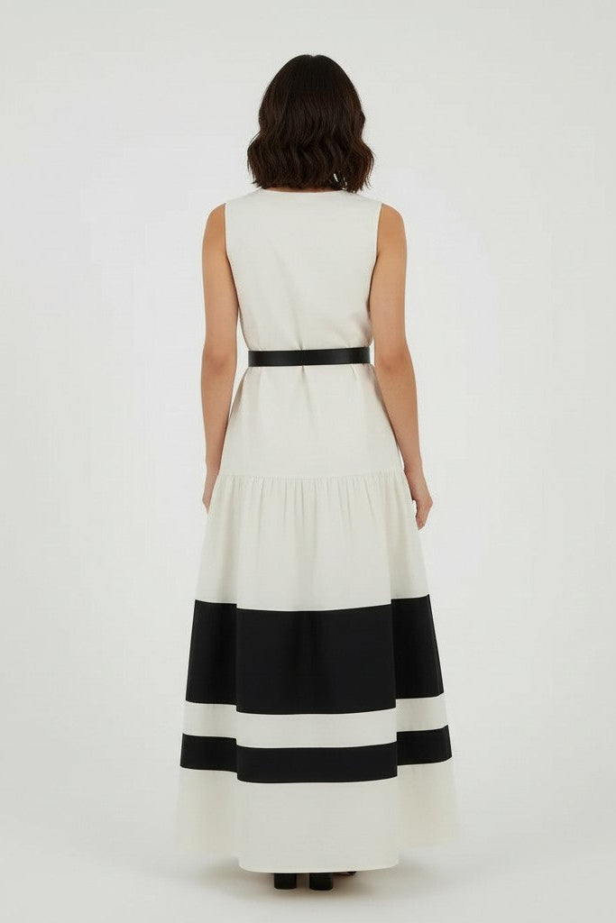 Back of a woman wearing a off-white and black striped dress on a plain background.