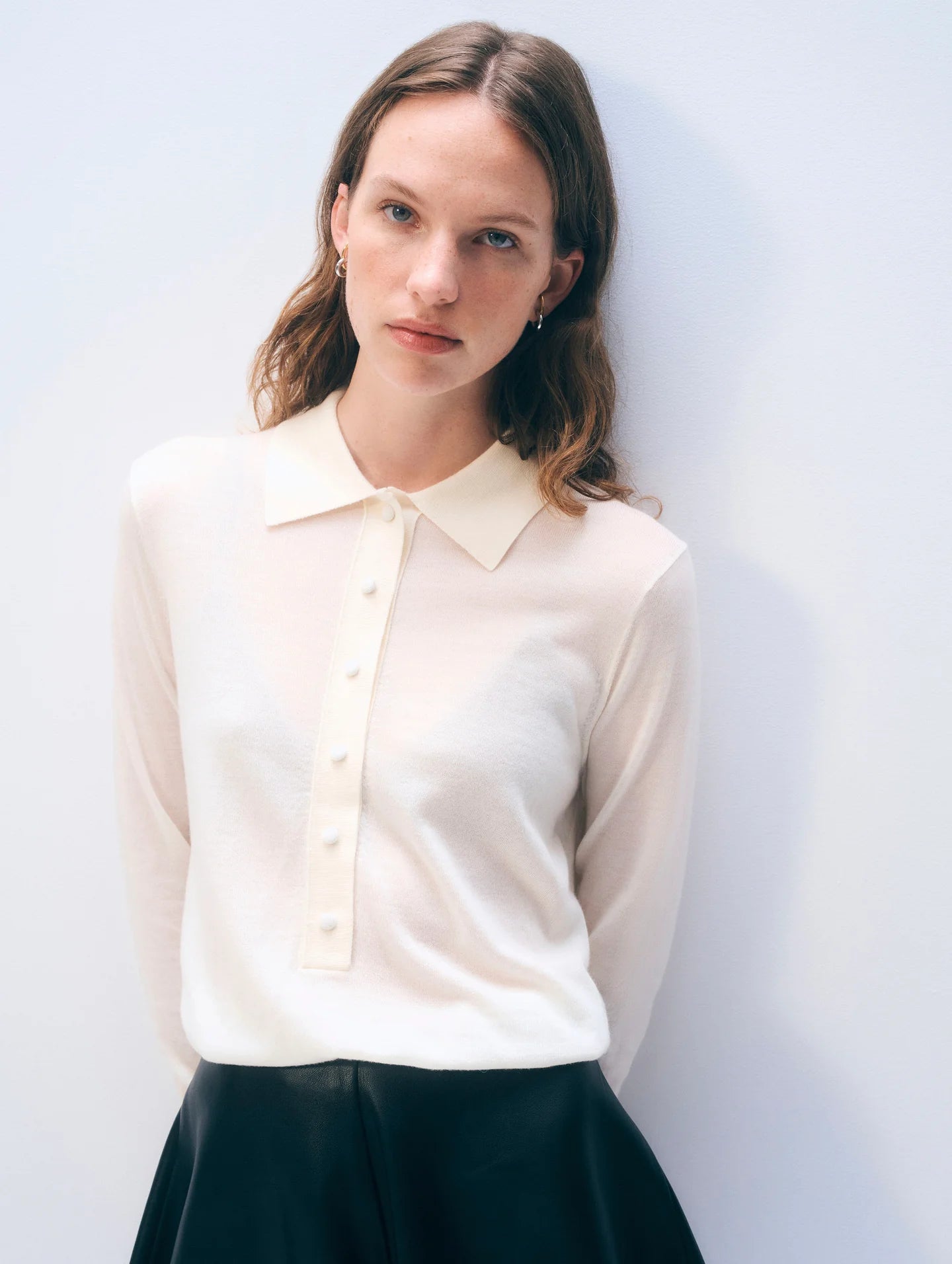 Woman wearing a cream blouse against a plain background.