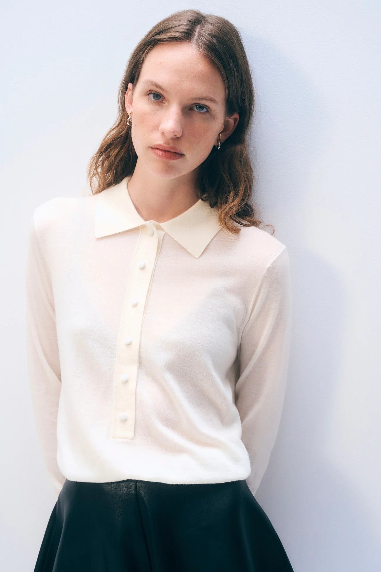 Woman wearing a cream blouse against a plain background.