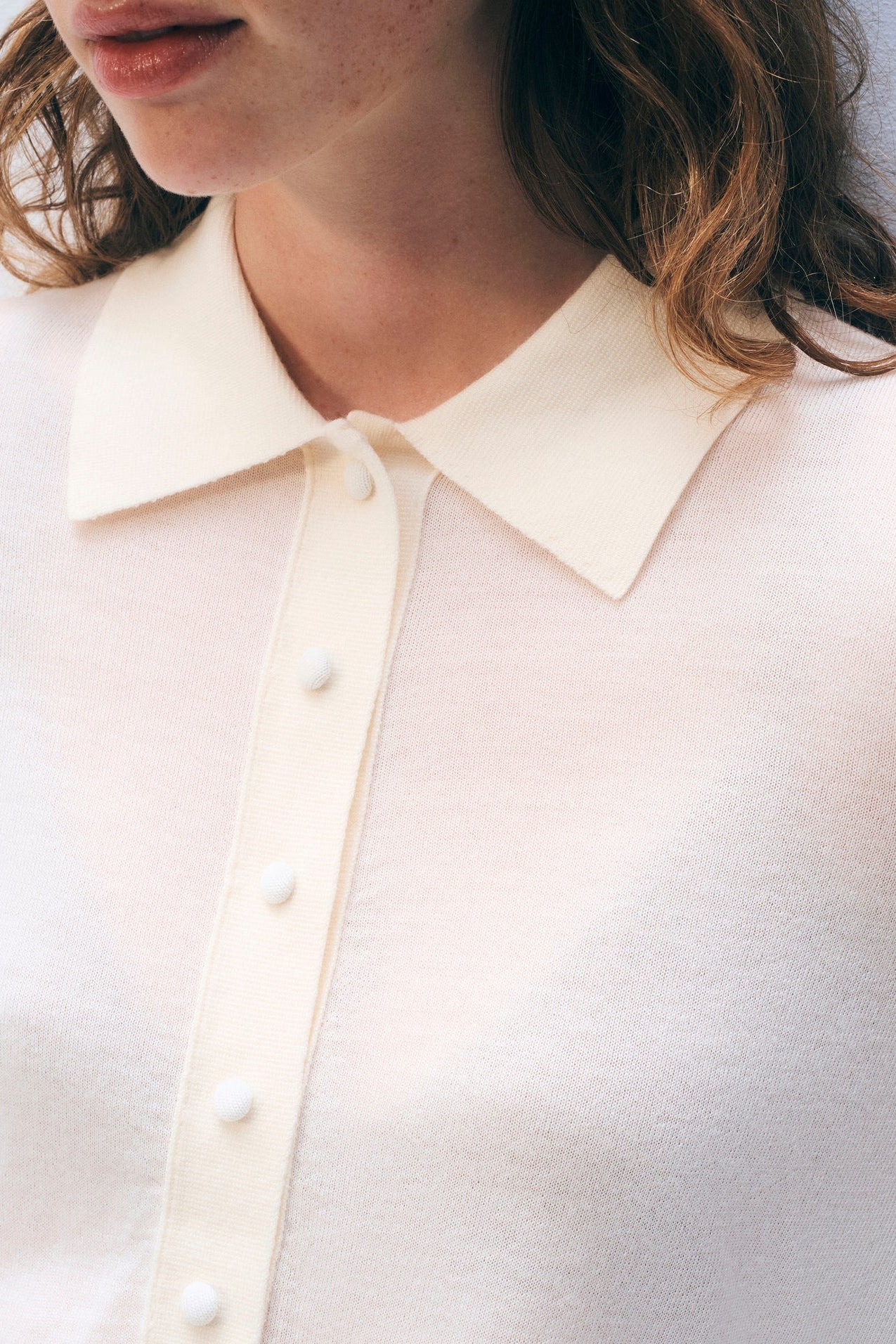 Close-up of a person wearing a light-colored shirt with a collar and buttons.