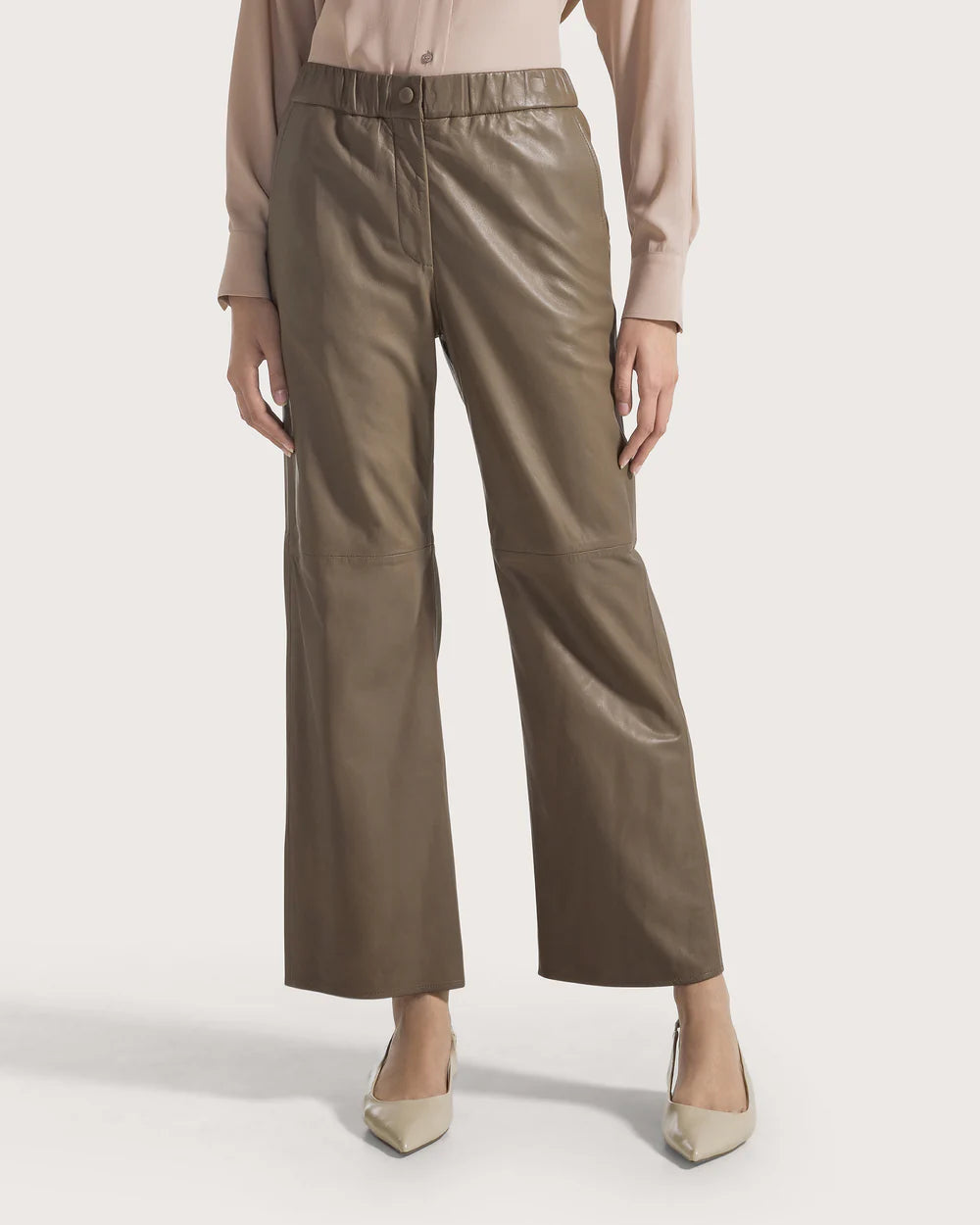Woman wearing taupe pants on a white background.