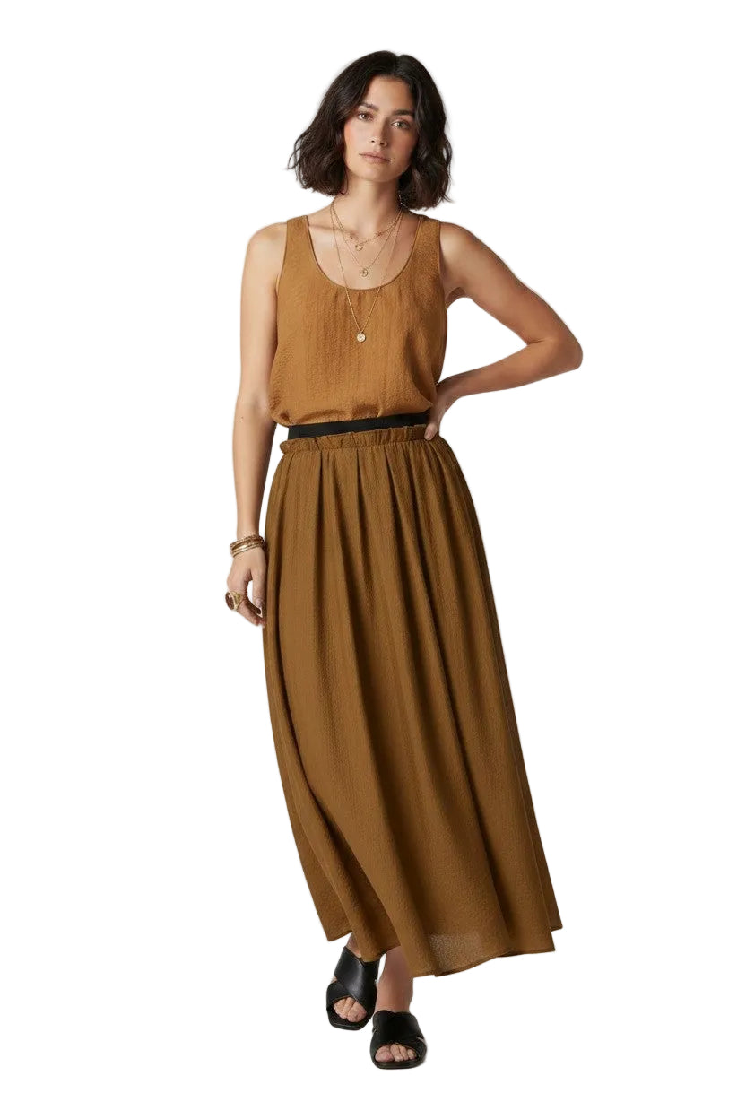 Woman wearing a brown sleeveless top and long skirt on a white background.