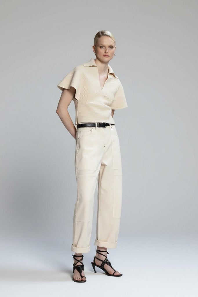 Woman wearing a beige outfit with a belt on a plain background.