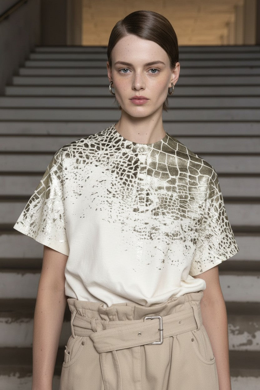 Model wearing a textured gold top and beige pants on a staircase background.