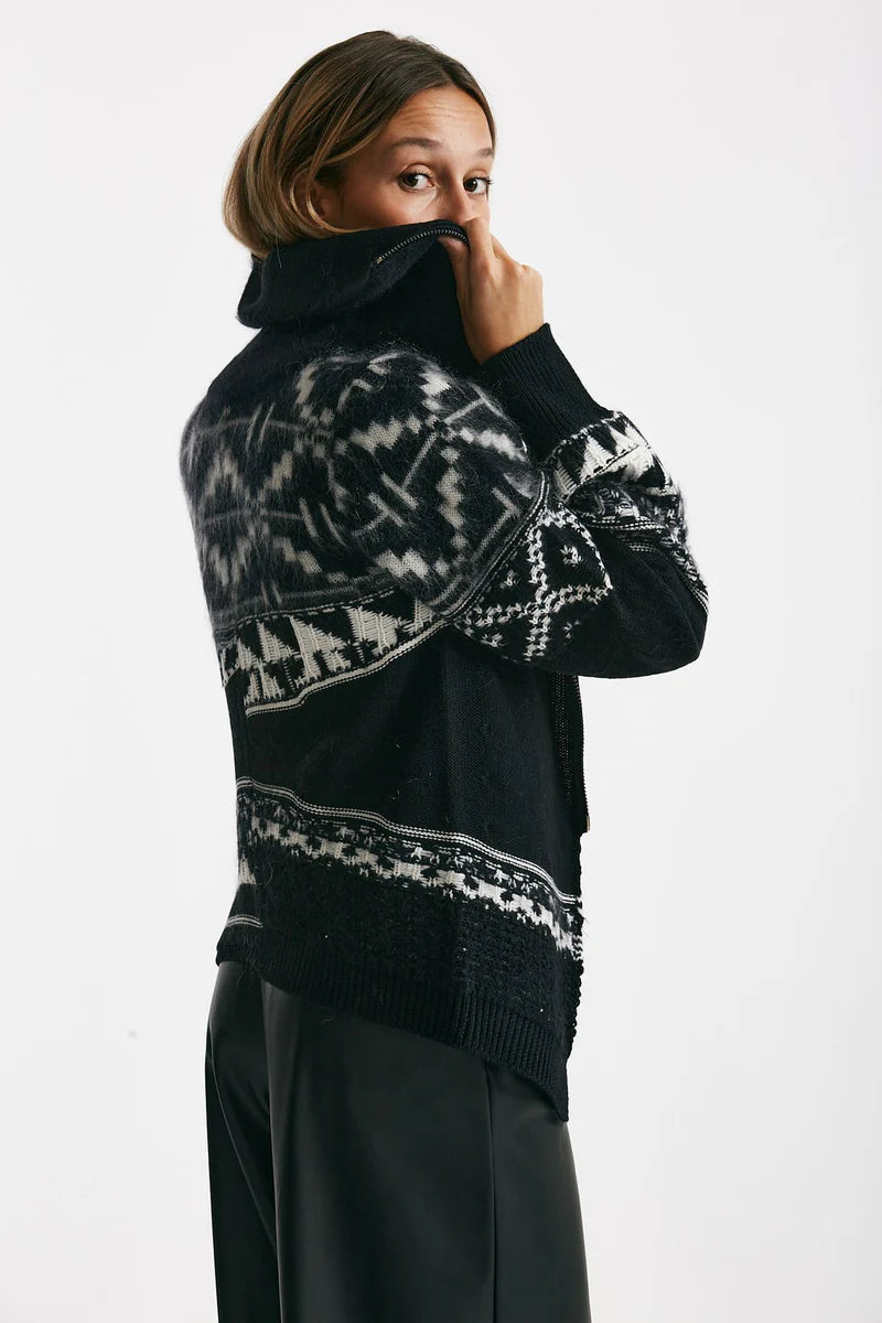 Woman wearing a black and white patterned sweater on a white background.