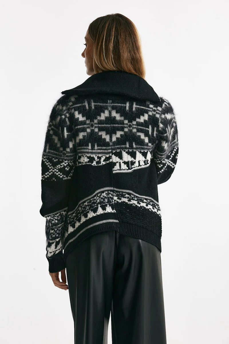 Back of a woman wearing a black and white patterned cardigan on a white background.