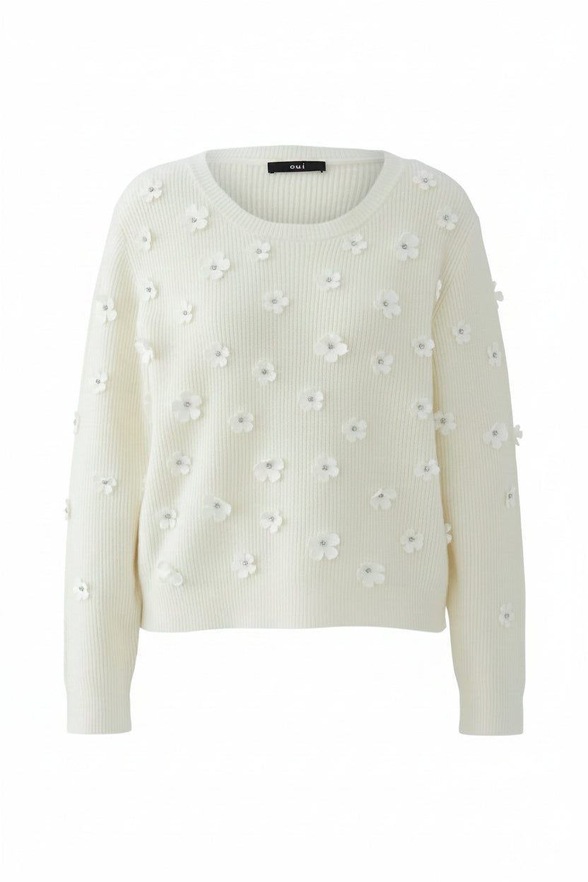 Cream-colored sweater with floral embellishments on a white background.