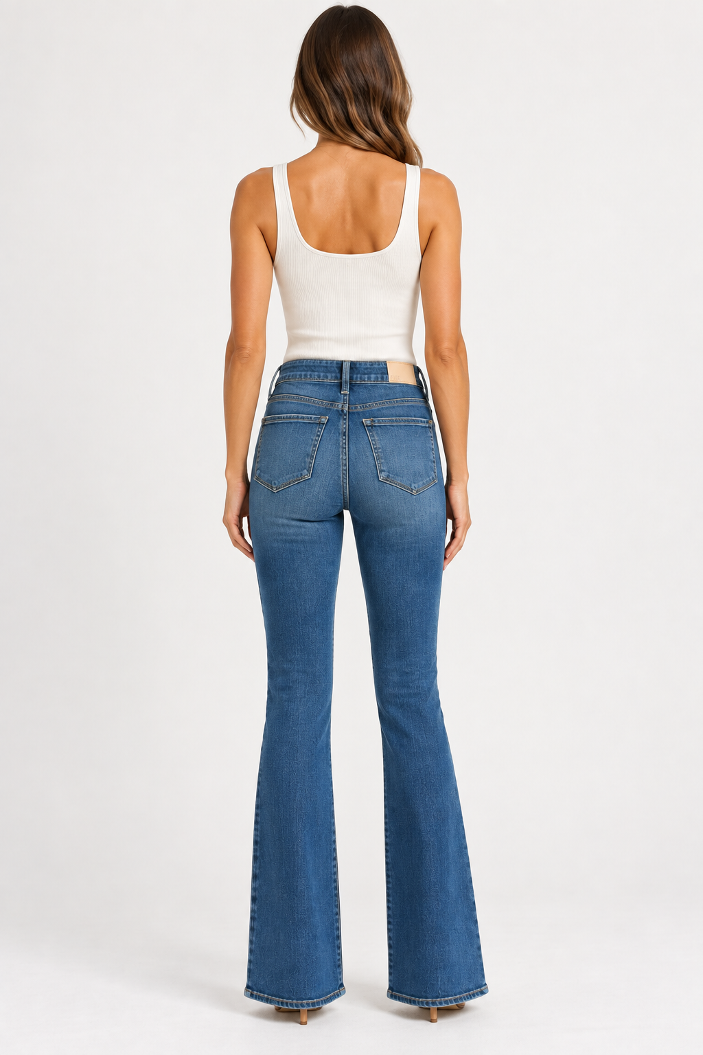 Back view of model wearing PAIGE Laurel Canyon medium blue bootcut jeans, featuring classic back pockets, PAIGE waistband patch, and full-length flared legs.