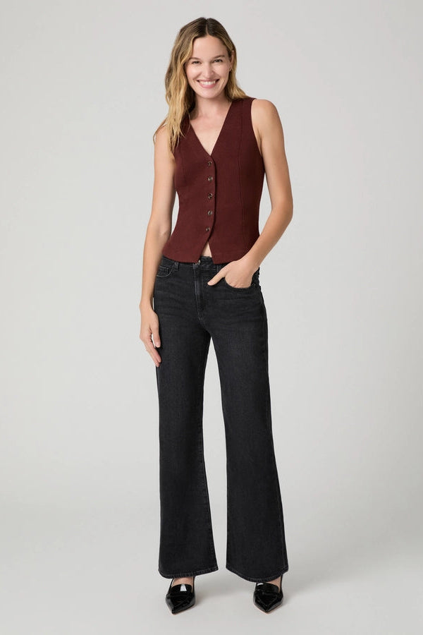 Model wearing PAIGE Sofia black flare jeans with a burgundy vest and black pointed-toe heels.