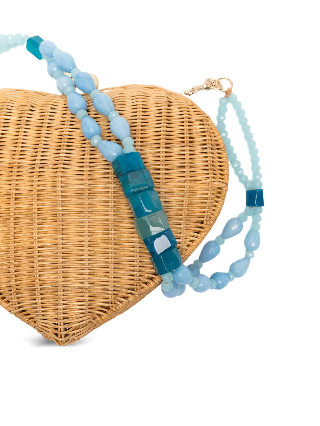 Heart-shaped wicker bag with a blue beaded strap on a white background.