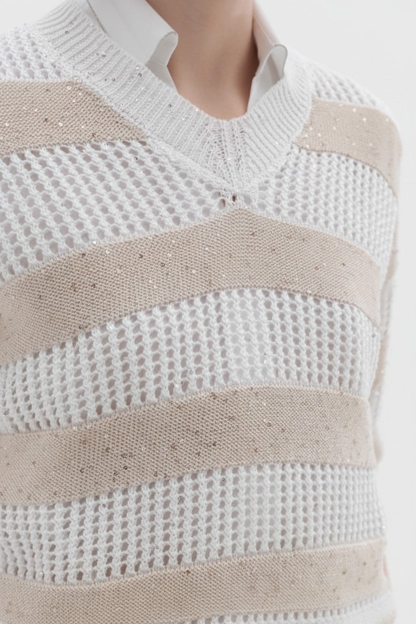 Close-up of a beige and white striped sweater on a plain background.