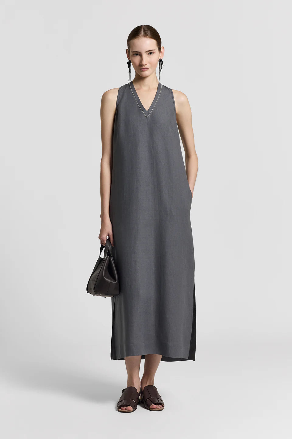 Woman wearing a blue gray sleeveless dress on a white background.